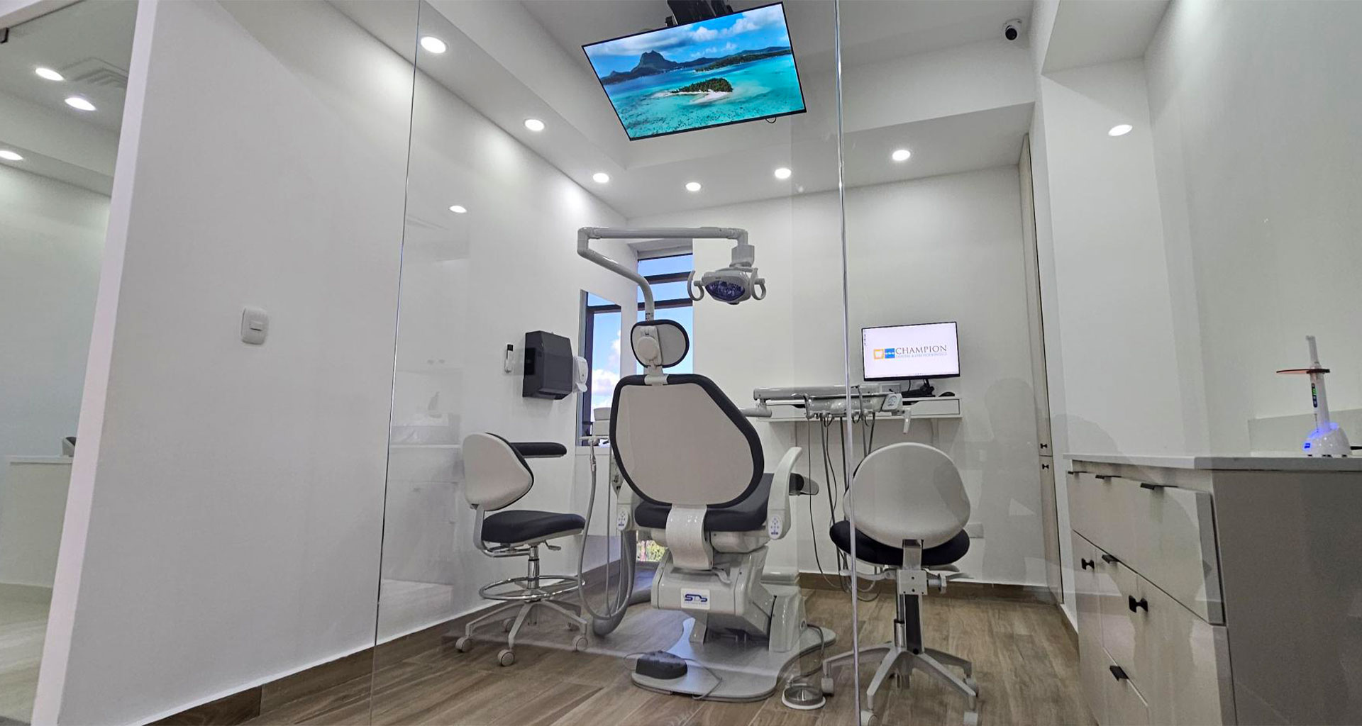 A modern dental office with a large mirror, a fish tank, and a chair for patient seating.