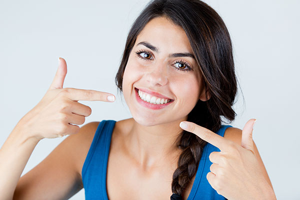 Smiling woman with hand on hip, pointing to camera with other hand.