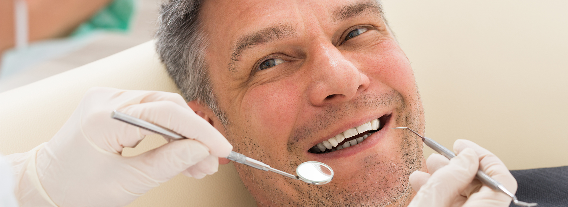 A man in a dental chair being attended to by a dentist, with visible dental tools and equipment.