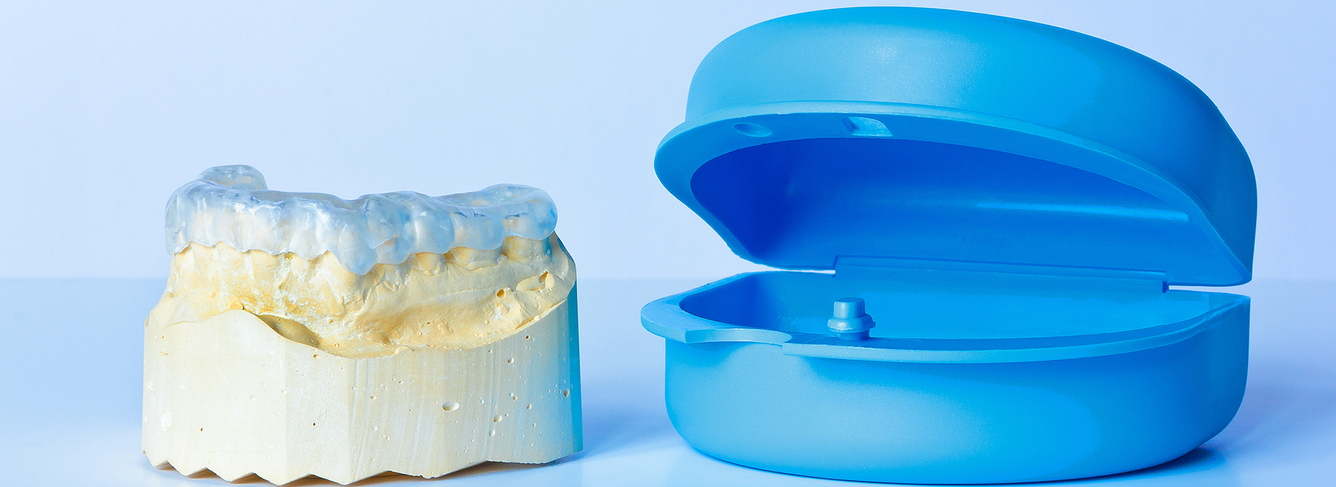 An image featuring a blue toothbrush and a yellow dental implant, both on a white background.