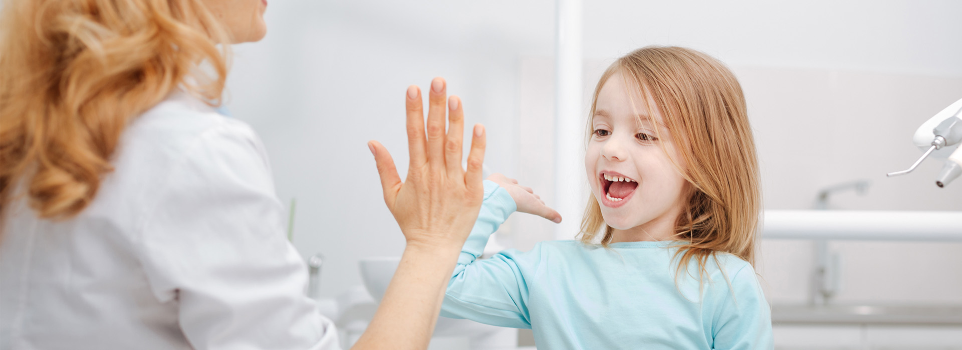 A woman and a young girl are interacting in a bathroom setting, with the child reaching out towards the adult.