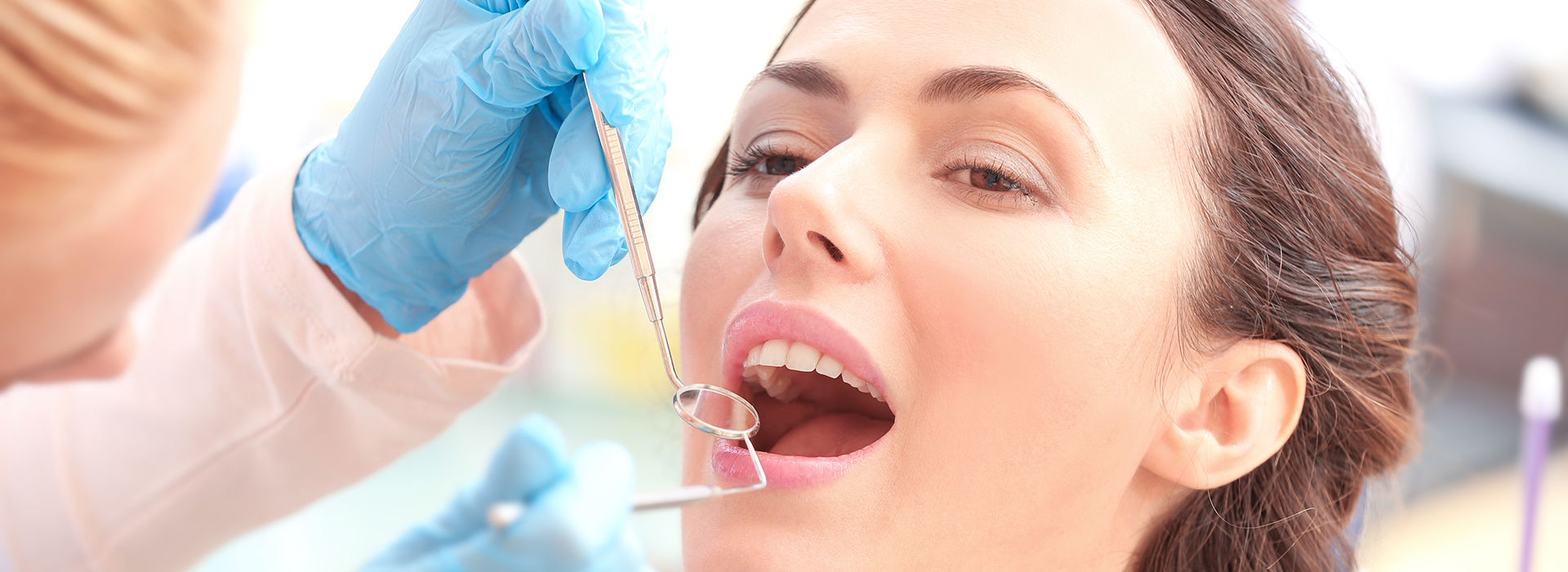 An image featuring a woman receiving dental treatment, with a focus on the dental professional performing the procedure.