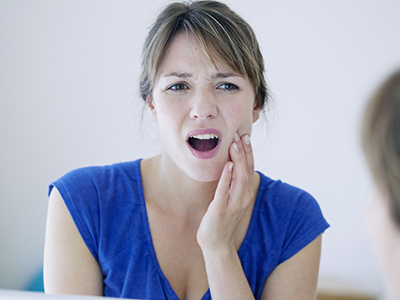 The image shows a woman with her mouth open, displaying a toothbrush in her mouth, and she appears to be making an expression of surprise or shock.