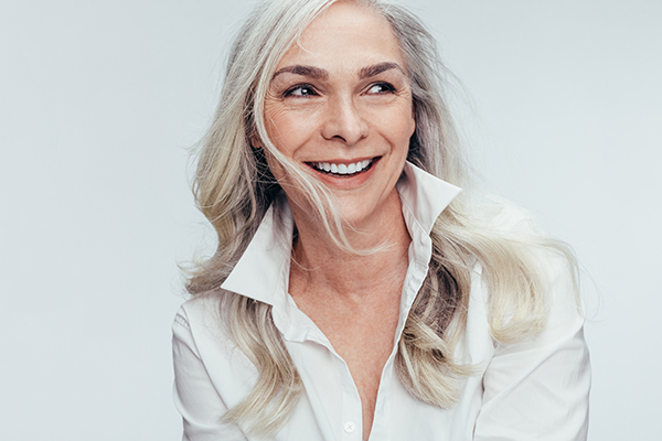 A woman with blonde hair and a neutral expression, smiling slightly, posing against a white background.