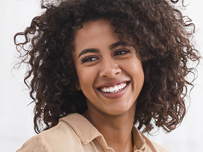 A woman with curly hair and a warm smile, looking directly at the camera.